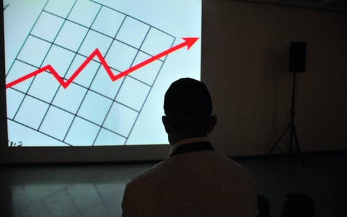 Alt-text: A person looking at a chart showing a rising trend