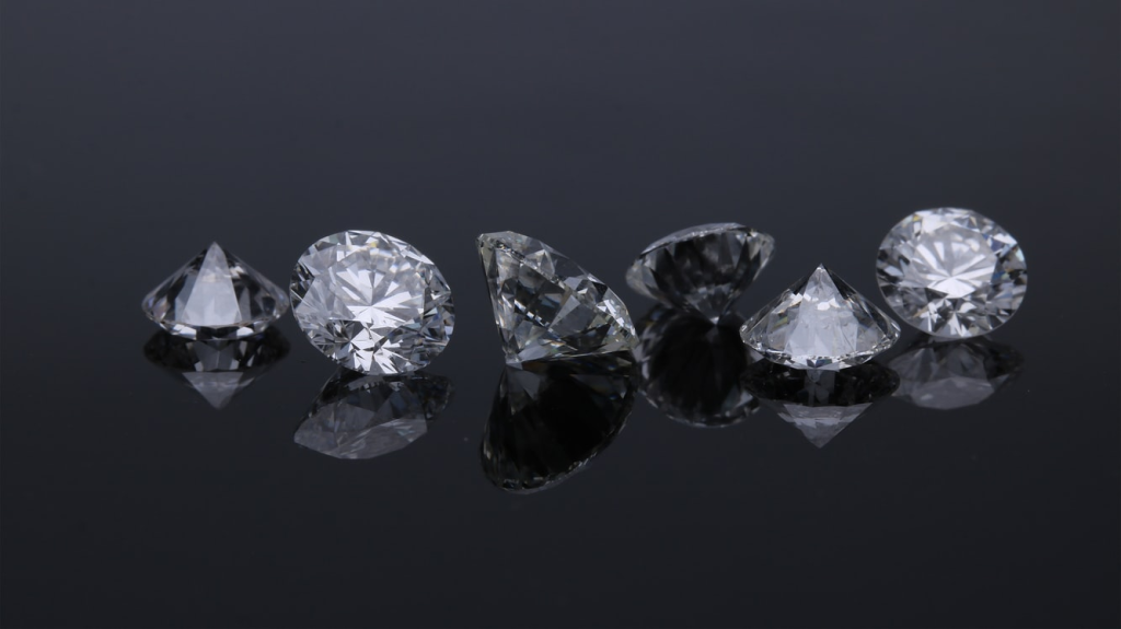 Six diamonds resting on a shiny surface.