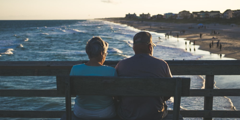 An old retired couple enjoying the beach from the bench