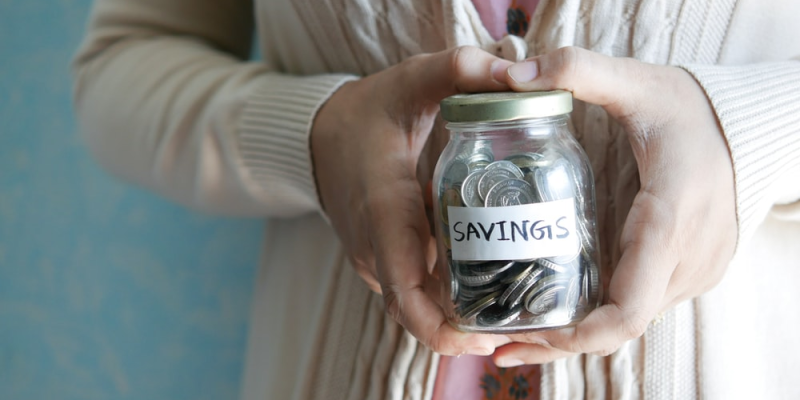 A person holding a jar of coins as savings