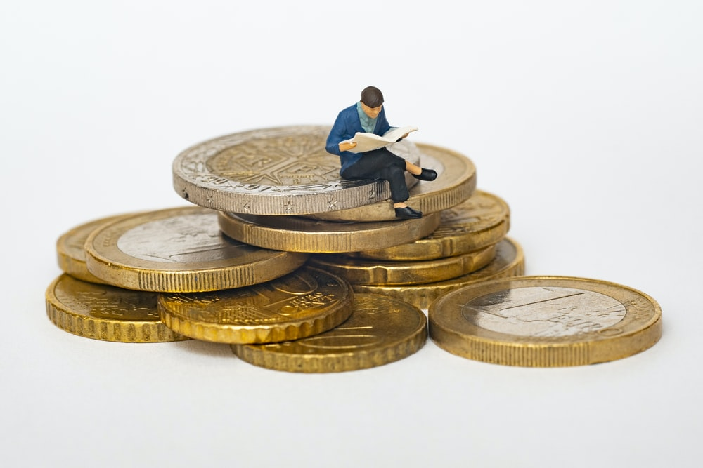 An animated person reading on top of some gold coins