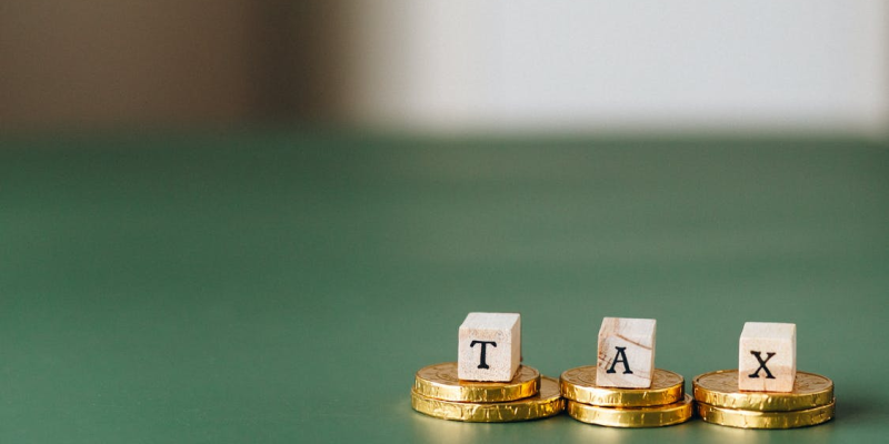 Alphabetical blocks reading “tax” on top of gold coins.