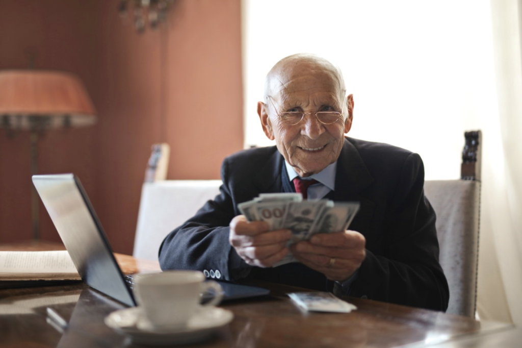 An elderly man holding money.