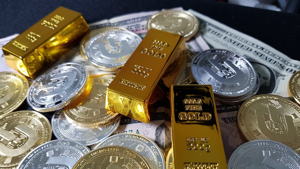 Gold bars and silver coins lying on American currency