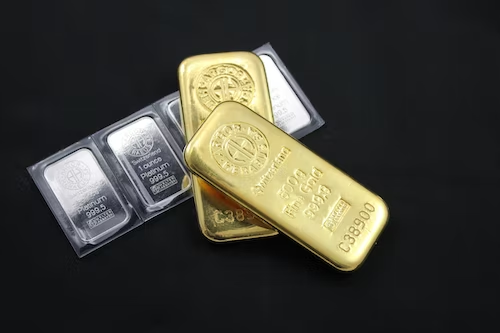 Silver and gold bars placed against a plain, black background