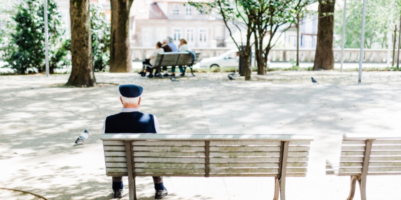 An elderly man sitting on a bench outdoors