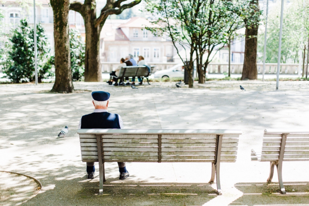 An elderly man sitting on a bench outdoors
