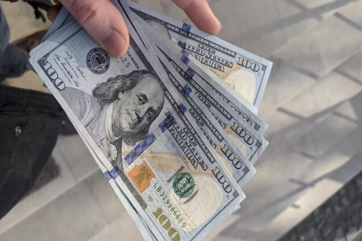 An individual holding hundred dollar bills