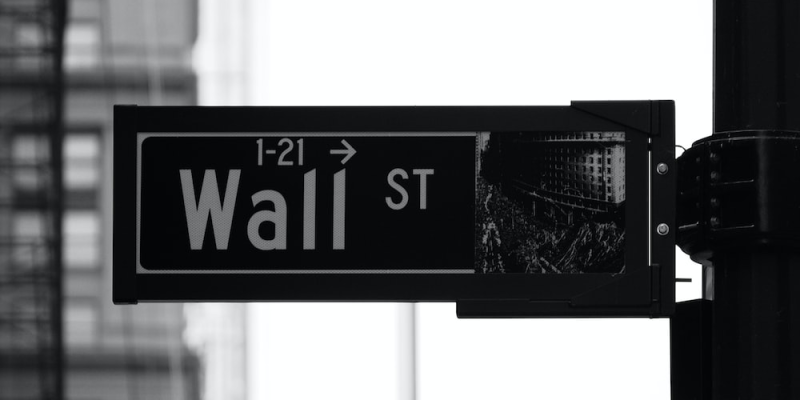 a grayscale photo showing Wall St signage.