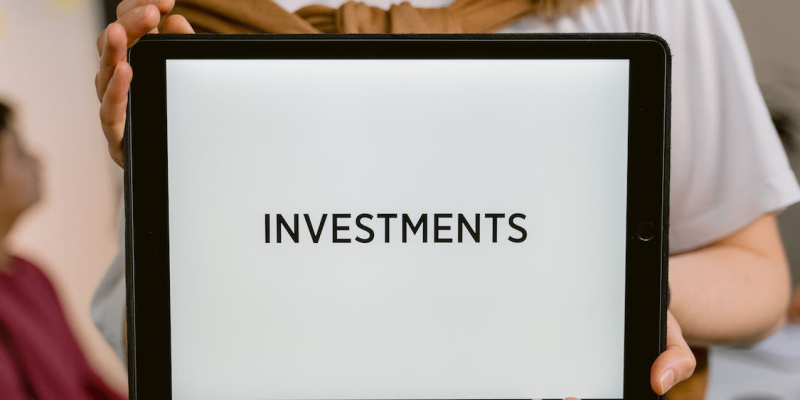 a close-up shot of a person holding a tablet saying investments.